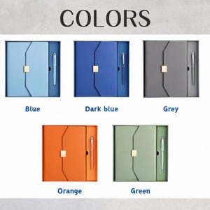 May include: An assortment of five boxed sets, each containing a notebook and pen. The sets are in various colors: blue, dark blue, grey, orange, and green. The word "COLORS" is displayed at the top of the image.