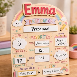 May include: A wooden arched sign for a child's first day of school featuring the name Emma in red letters. The board includes pastel rainbow graphics, clouds, stars, and a pencil. It displays text fields for age, height in inches, favorites, date, and teacher.