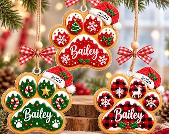 May include: Three paw-shaped Christmas ornaments hanging from twine with red and white checkered bows. Each ornament features a Santa hat with the year 2026, the name Bailey in white script, and festive patterns including snowflakes, trees, and candy canes.