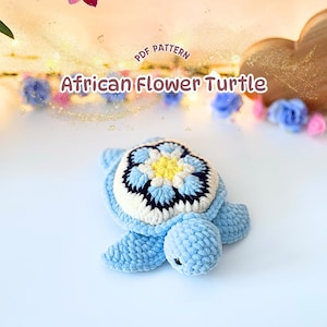 Puede incluir: Un juguete de tortuga de ganchillo con cuerpo azul claro y un caparazón con diseño de flor africana en amarillo, blanco, azul claro y azul oscuro. El texto PDF PATTERN African Flower Turtle aparece sobre el objeto.