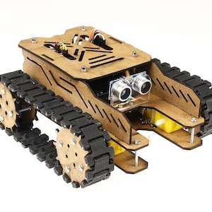 Peut inclure: Un kit de robot en bois avec des chenilles noires et un ensemble de capteurs. Le robot a un corps rectangulaire avec des découpes et est assemblé avec des vis. Les chenilles sont en caoutchouc noir et sont fixées au cadre en bois. Idéal pour l'apprentissage.