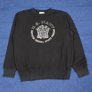 K&ouml;nnte beinhalten: Schwarzes Sweatshirt mit Rundhalsausschnitt und dem Text "U.S. NAVY" in einem kreisf&ouml;rmigen Design mit einem Emblem. Das Sweatshirt hat lange &Auml;rmel und gerippte B&uuml;ndchen und Saum. Der Text "NORTHERN REGIONAL SPORTS PROGRAM" ist ebenfalls aufgedruckt.