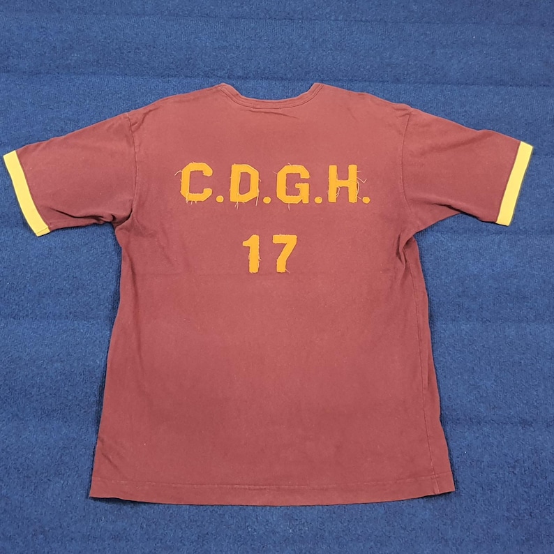 May include: A white ceramic mug with a black handle and the text "But First, Coffee" in a bold, black font. The mug is set against a blurred background, suggesting a cozy setting.