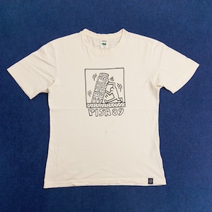 Puede incluir: Una camiseta blanca con un gr&aacute;fico en blanco y negro de una persona empujando la Torre Inclinada de Pisa. El gr&aacute;fico est&aacute; rodeado de un cuadrado negro con el texto "PISA 89" debajo.