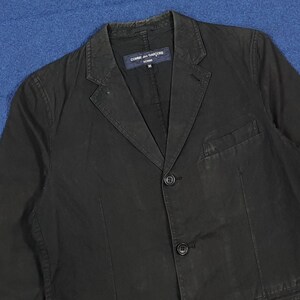 May include: A black blazer with a notched lapel, two-button closure, and a single chest pocket. The blazer has a tailored fit and a label that reads "COMME des GAR&Ccedil;ONS HOMME".