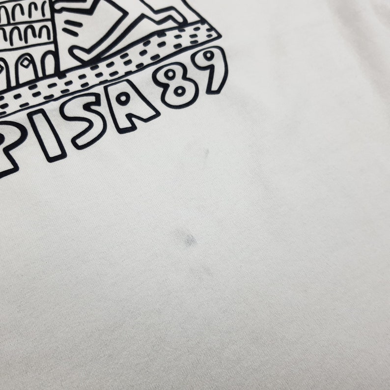 Puede incluir: Una camiseta blanca con un estampado gr&aacute;fico negro de la Torre Inclinada de Pisa y el texto "PISA 89".