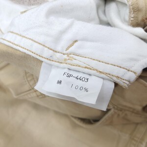 May include: Close-up of tan-colored denim pants with a white interior. A white tag displays the text "FSP-4403", the Japanese character for cotton, and "100%". The pants have visible stitching.