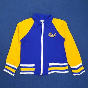 Könnte beinhalten: Eine blaue und gelbe Reißverschlussjacke mit weißen Streifen und dem Schriftzug "Cal Berkeley" auf der Vorderseite.
