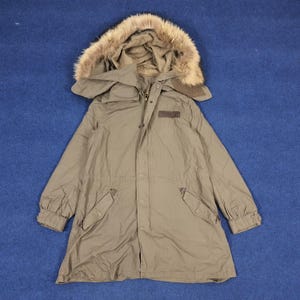 May include: A long, olive green parka with a fur-lined hood. The parka has a zipper closure, two flap pockets, and a drawstring waist.