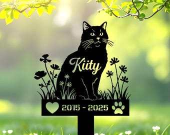 May include: Black metal cat memorial stake with the name "Kitty" in script. The stake features a heart, paw print, and the years 2015-2025. Decorative flowers and grass surround the cat silhouette.