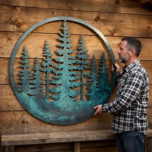 May include: A large circular metal wall art piece featuring a detailed cutout silhouette of a dense pine forest. The metal has a weathered, oxidized teal and copper patina finish, creating a textured appearance within the circular frame.