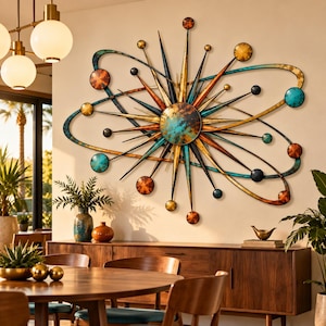 May include: A large metal wall sculpture featuring a central sunburst design with radiating spikes and orbiting rings. The piece incorporates spheres in shades of copper, teal, and black, creating a celestial-inspired arrangement of geometric shapes.