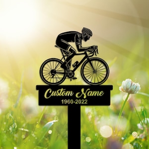 May include: Black silhouette of a cyclist riding a bicycle with the text "Custom Name 1960-2022" on a black plaque.