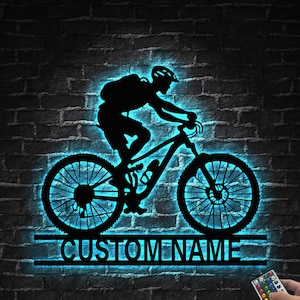 Pode incluir: Uma silhueta azul de uma pessoa a andar de bicicleta de montanha com o texto "CUSTOMNAME" abaixo. A imagem é iluminada por trás com luz azul.