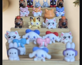 May include: A collection of small, colorful, cartoon animal figurines with various expressions. The figurines are arranged on a wooden shelf, with some sitting on the shelf and others hanging off the edge. The figurines are made of plastic and have a variety of colors, including red, blue, green, yellow, and pink.