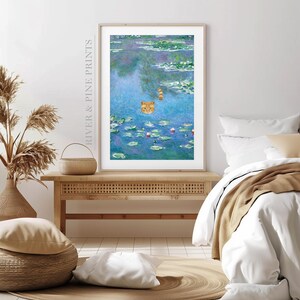 May include: A framed print of a painting depicting a cat swimming in a pond with water lilies. The cat is orange and white and is looking at the viewer. The water lilies are pink and green and the water is blue.