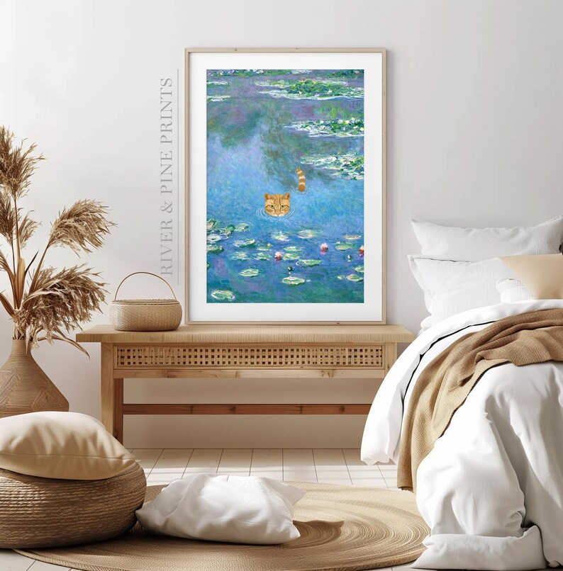 May include: A framed print of a painting depicting a cat swimming in a pond with water lilies. The cat is orange and white and is looking at the viewer. The water lilies are pink and green and the water is blue.