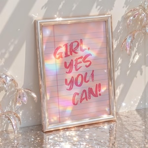 以下が含まれることがあります： ピンク色のスクリプトで「GIRL. YES YOU CAN！」と書かれた、ピンク色の罫線入り紙の背景の額入りプリント。フレームはシルバーで、画像は虹色の光の効果があり、ソフトでドリーミーな美しさです。