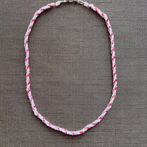 May include: A white and red beaded necklace with a silver clasp.