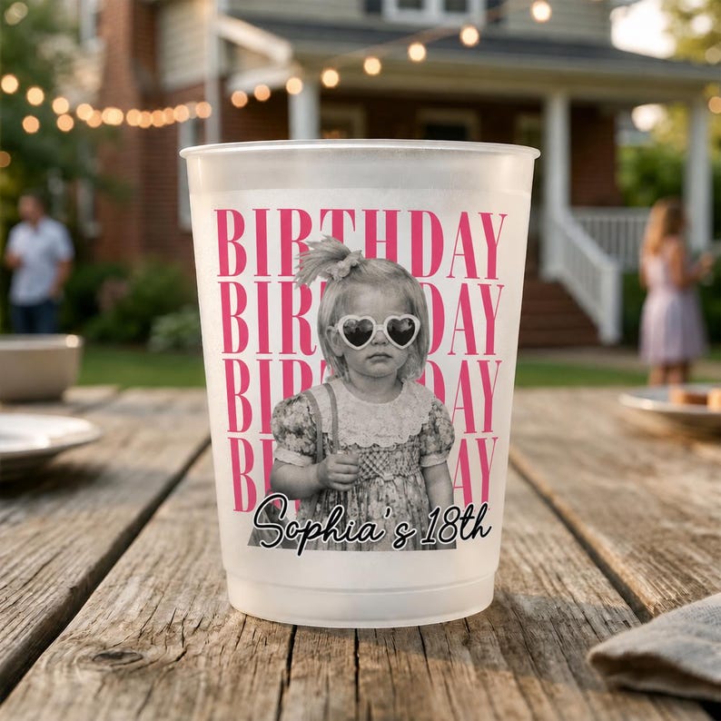 May include: A white plastic cup with a pink "BIRTHDAY" repeating text design. A black and white photo of a young girl wearing heart-shaped sunglasses is in the center. The text "Sophia's 18th" is below the photo.