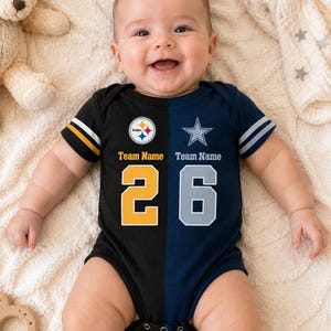 May include: A short-sleeve baby bodysuit featuring a split design. The left side is black with a yellow and white Steelers logo, the text Team Name, and the number 26 in yellow. The right side is navy blue with a silver star, Team Name, and the number 26.