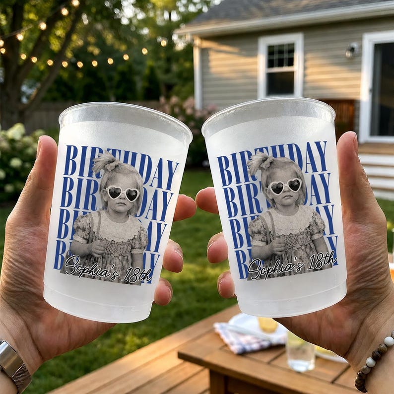 May include: Two frosted plastic cups with a birthday theme. Each cup features a black and white photo of a young girl wearing heart-shaped sunglasses, with the words "BIRTHDAY" and "Sophia's 18th" in blue.