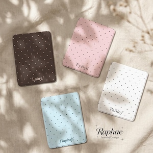 May include: Four rectangular compact mirrors featuring a polka dot pattern in brown, pink, white, and light blue. Each mirror is personalized with a name: Laura, Evelyn, Paisley, and Hannah. The text Raphae JewelryDesign is visible in the corner.