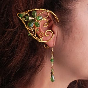 May include: Gold ear cuff with a green flower design and a matching green beaded dangle earring.