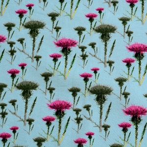 Puede incluir: Patr&oacute;n repetitivo de cardos sobre un fondo azul claro. Los cardos tienen flores rosas vibrantes y capullos y tallos espinosos de color verde oscuro. Ilustraci&oacute;n bot&aacute;nica para tela o papel pintado.