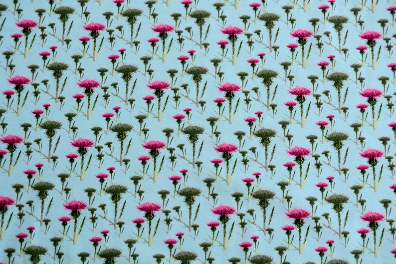 Puede incluir: Un patr&oacute;n repetido de cardos sobre un fondo azul claro. Los cardos tienen tallos y hojas verdes, con capullos verde oscuro y cabezas de flores de color rosa vibrante. El dise&ntilde;o est&aacute; espaciado uniformemente.
