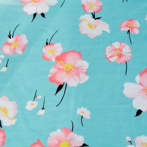 May include: A turquoise fabric with a repeating pattern of pink and white flowers. The flowers have a pink center and white petals.