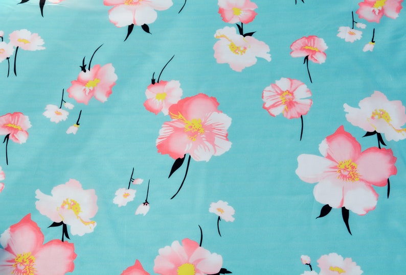 May include: A turquoise fabric with a repeating pattern of pink and white flowers. The flowers have a pink center and white petals.