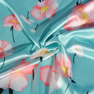 May include: A turquoise blue satin fabric with a floral pattern. The flowers are pink with white centers and black stems.