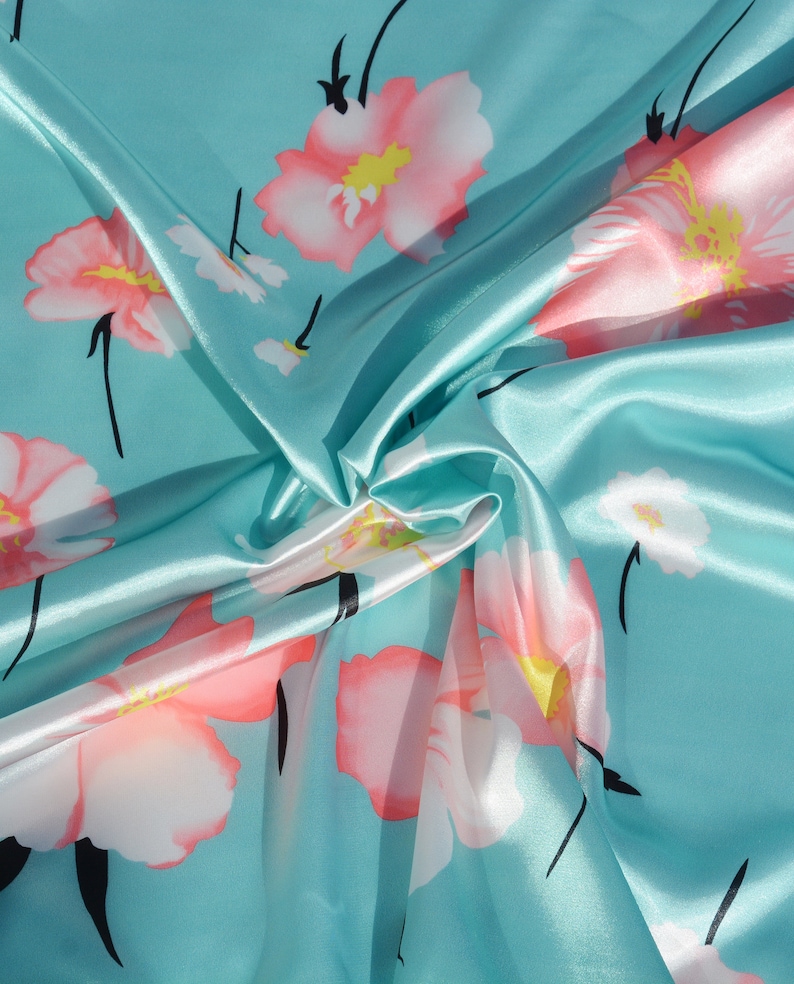 May include: A turquoise blue satin fabric with a floral pattern. The flowers are pink with white centers and black stems.