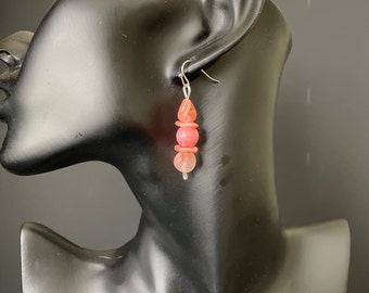 Earrings with round and flat peachy pink beads on a silver hook