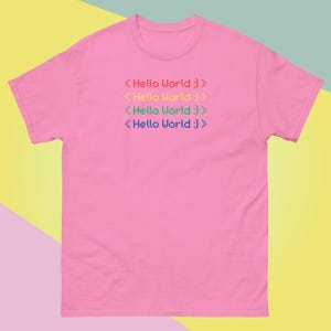 May include: Pink t-shirt with the text "<Hello World :)>" repeated four times in different colors.