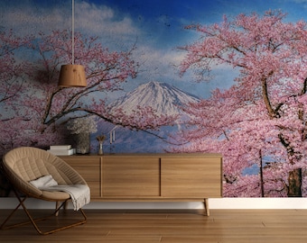May include: A wooden cabinet with two doors sits in front of a wall mural depicting a mountain range with cherry blossoms in bloom. The cabinet has a light wood finish and a modern design.