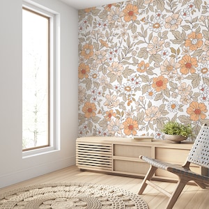 May include: A light wood media console with a floral wallpaper backdrop. The console has a light wood finish and features a series of horizontal slats on the front. The wallpaper features a repeating pattern of orange and brown flowers on a white background.