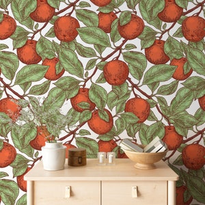 Op de afbeelding: Een houten dressoir met twee laden tegen een witte achtergrond met een herhalend patroon van rode appels en groene bladeren.