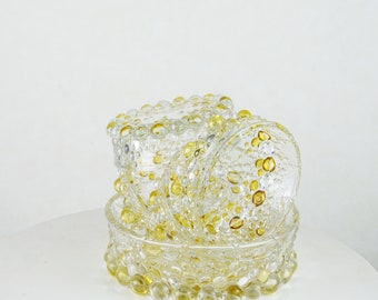 May include: A set of three clear glass bowls with a textured surface. The bowls are decorated with small yellow glass beads.