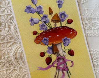 May include: A rectangular art print on a yellow background featuring a large red and white spotted mushroom, smaller brown mushrooms, purple bell-shaped flowers, and red strawberries. A pink ribbon is tied around the stem of the large mushroom.