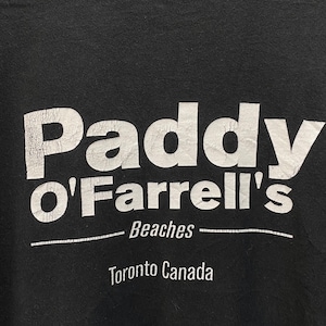 May include: Black t-shirt with the white text "Paddy O'Farrell's Beaches Toronto Canada". The text has a distressed, vintage look. The shirt is a casual wear item.