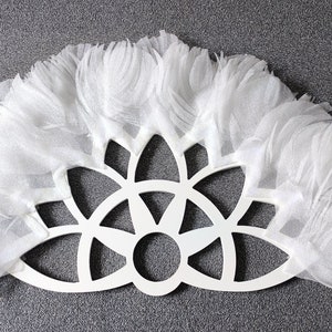 May include: White decorative wall hanging with a circular, geometric design and a fringe border.