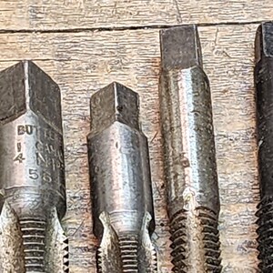 May include: Four metal tap and die sets with hexagonal heads. The set on the left has the text "BUTLER CANADA N14 55" engraved on the side.