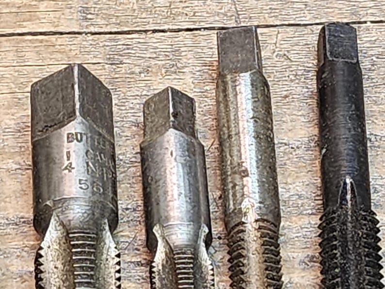 May include: Four metal tap and die sets with hexagonal heads. The set on the left has the text "BUTLER CANADA N14 55" engraved on the side.