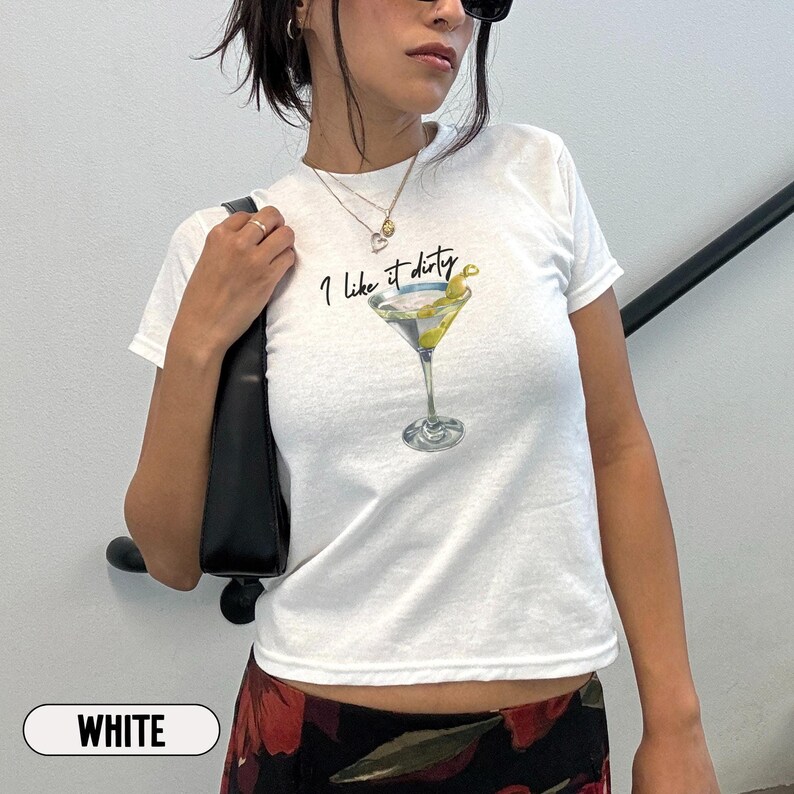 May include: White t-shirt with short sleeves featuring a martini glass with an olive and the text "I like it dirty".