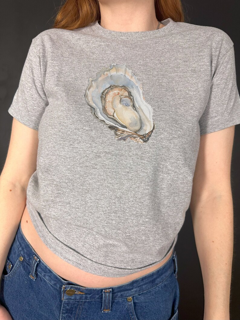 May include: A grey t-shirt with a watercolour illustration of an oyster shell on the front.