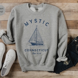 May include: A gray sweatshirt with the text "MYSTIC CONNECTICUT Est. 1854" and a sailboat graphic.