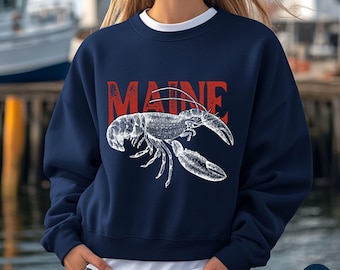 May include: Navy blue sweatshirt with a white lobster illustration and the word "MAINE" in red. The sweatshirt has a crew neck and a white undershirt is visible. The words "North Atlantic Apparel" are at the bottom left.