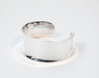 May include: A silver cuff bracelet with a smooth, polished finish.
